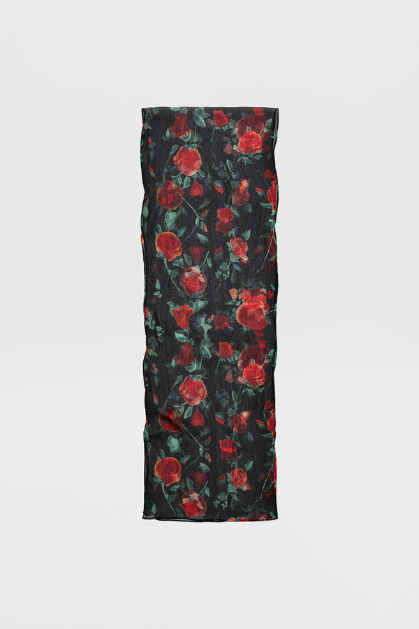 The Julien - Claudia Rose Black is a long, rectangular black scarf featuring red rose patterns with green leaves, displayed against a plain light background.