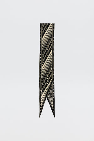 The Nara – Starstruck Black is a long, narrow pure silk scarf with cream diagonal stripes and small dots, finished with a pointed V-shaped tip, shown on a plain white background.