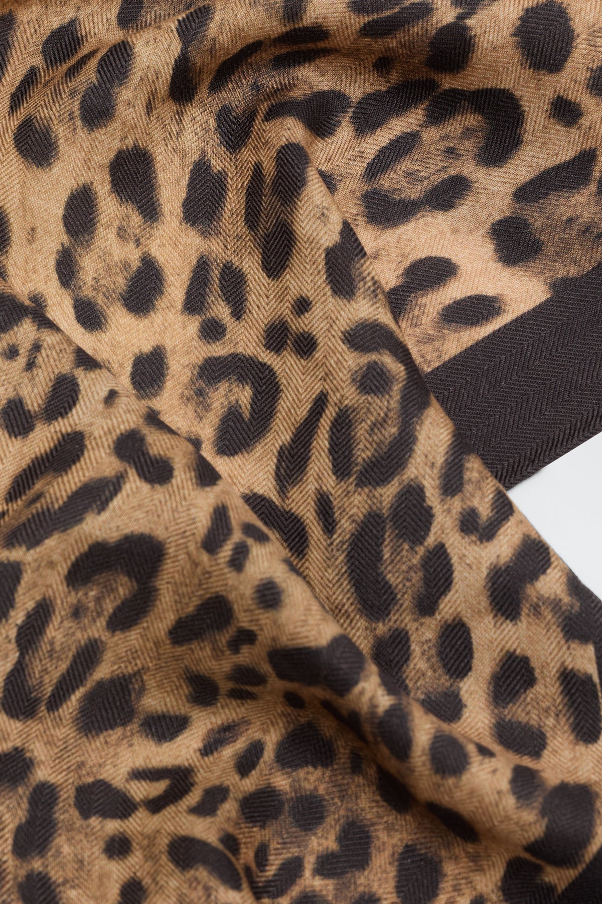 A close-up of the Elianna - Mila Leopard Brown fabric, featuring its brown and black leopard print pattern, highlighting the rich texture and wavy folds.