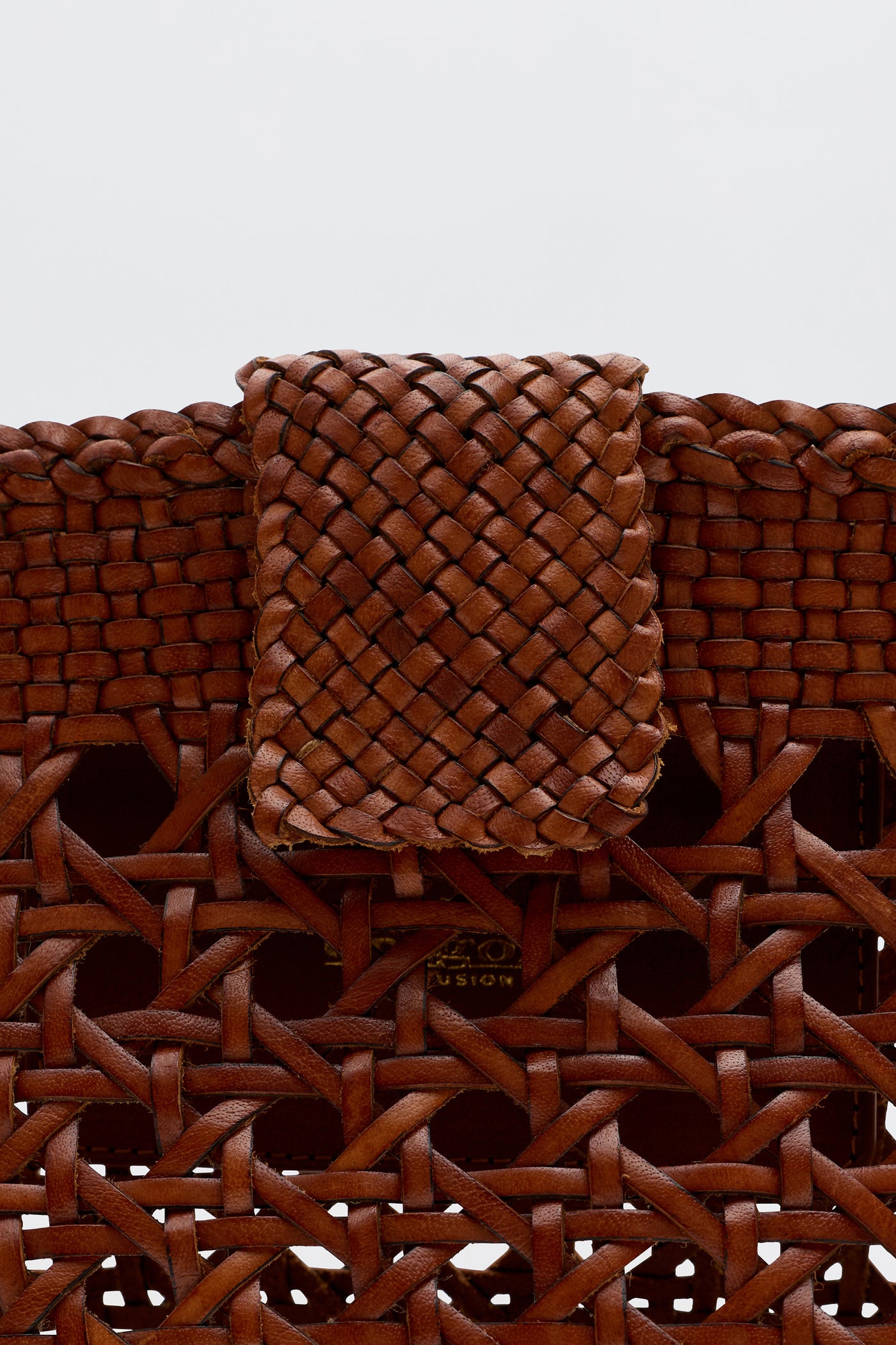 Close-up of the Lucine - Tan bag by Dragon Diffusion, featuring a detailed basket weave in brown leather with a flap closure. The bag highlights expert craftsmanship and textured woven leather.