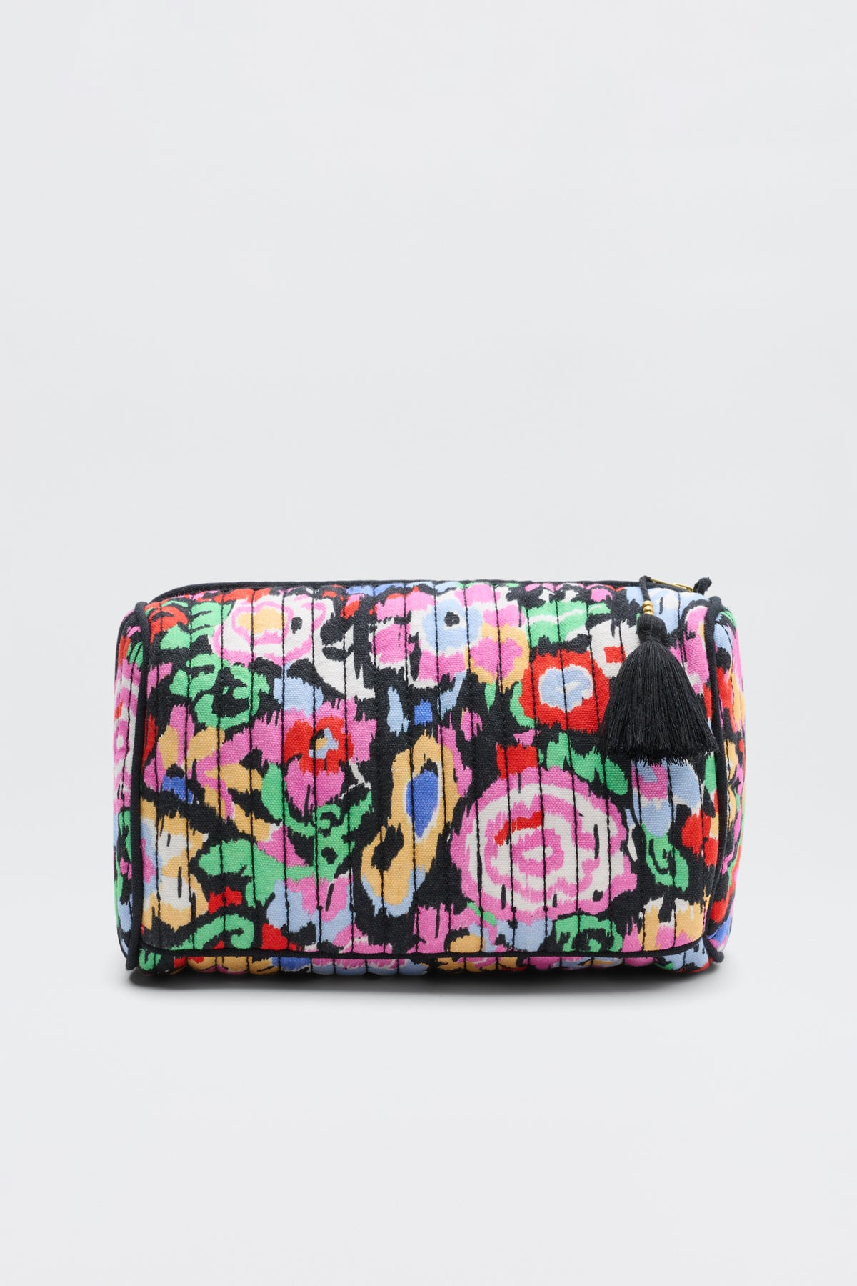 The Jadina - Ikat Bloom Charcoal is a rectangular pouch with a colorful abstract floral pattern and vertical black lines, accented by a small black tassel on the zipper, shown against a plain light gray background.