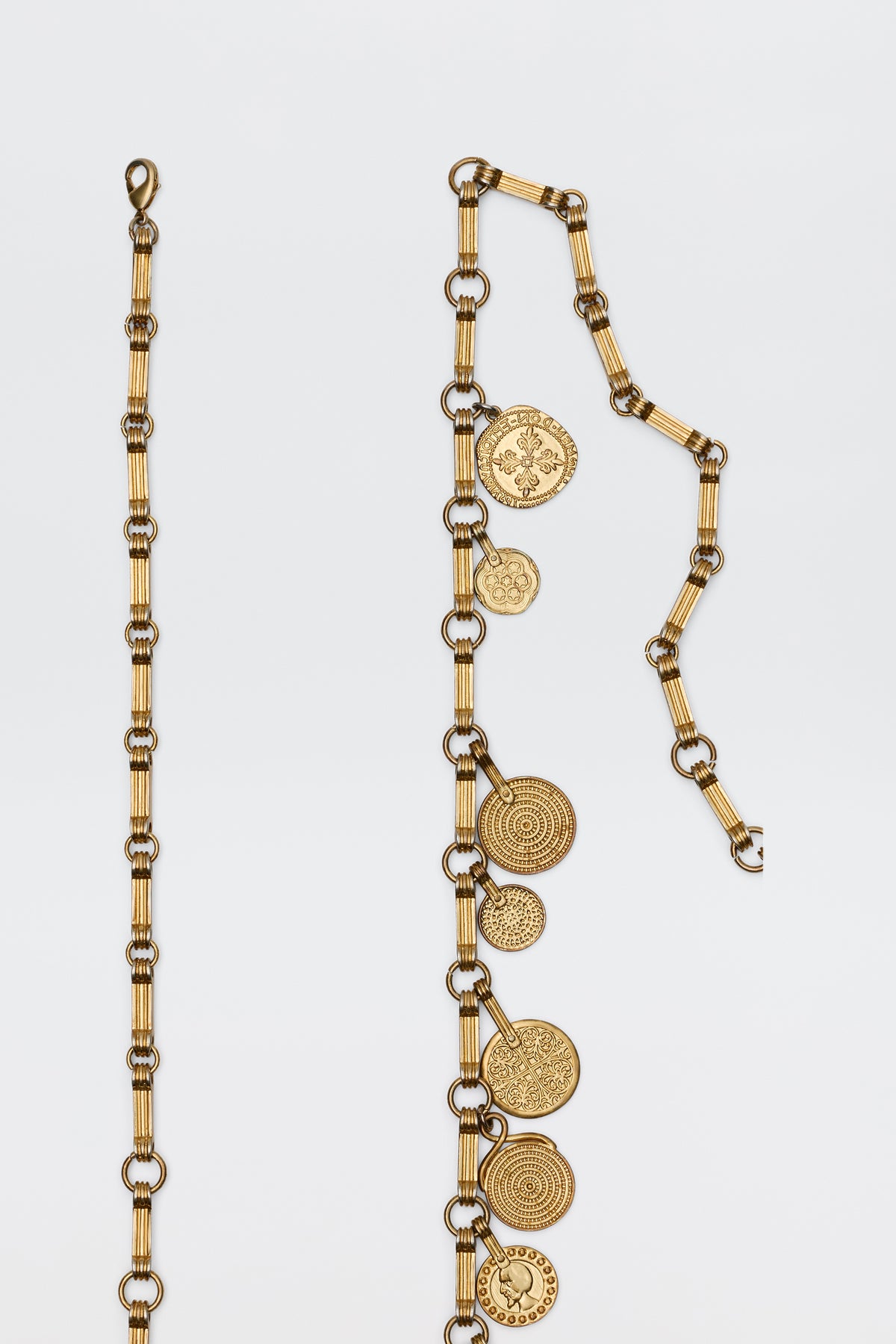 The Isolde - Gold belt features circular coin charms and textured rectangular links in a gold-tone, displayed vertically against a white background—a vintage-inspired accessory to complement RIXO dresses.
