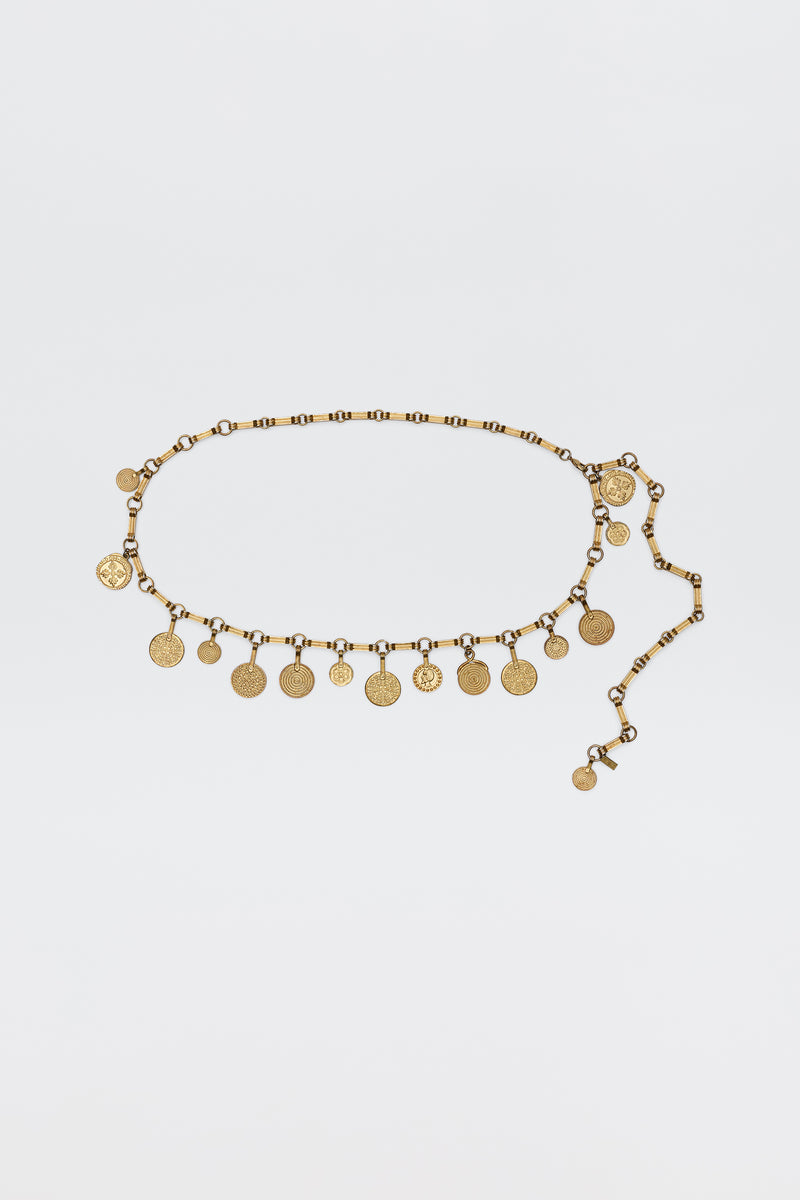The Isolde - Gold belt features evenly spaced coin-shaped charms on a linked chain, bringing vintage glamour—ideal for pairing with RIXO dresses. Shown on a simple white background.