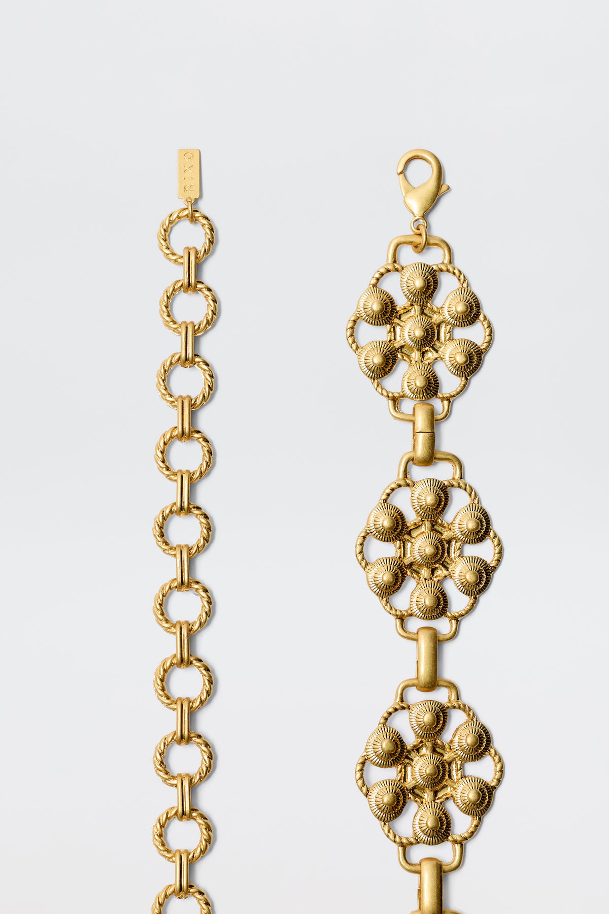 Tiana - Gold: Two gold bracelets on a white background—one with interlocking vintage-gold circles, the other with ornate floral links and textured details, reminiscent of a daisy-chain belt.