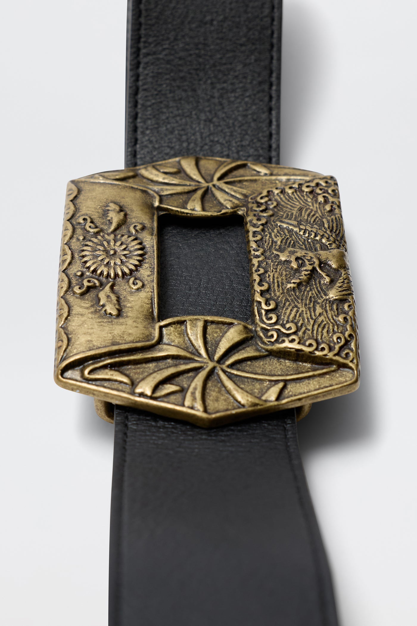 The Rhianna - Black is a black leather belt with an ornate, square brass buckle featuring intricate floral patterns and decorative swirls.