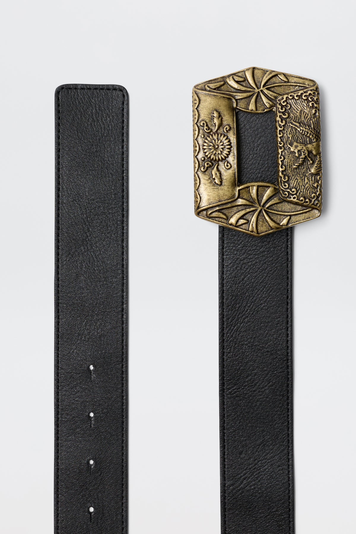 The Rhianna - Black belt features a large, ornate rectangular brass buckle with intricate floral and animal engravings, showcased against a plain light background.