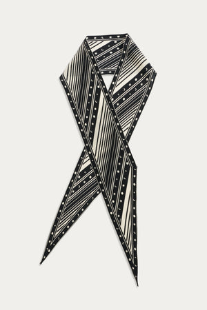 The Yelina - Starstruck Black silk scarf is displayed in a crisscross layout, highlighting its bold black and white diagonal stripes and small polka dots against a white background.