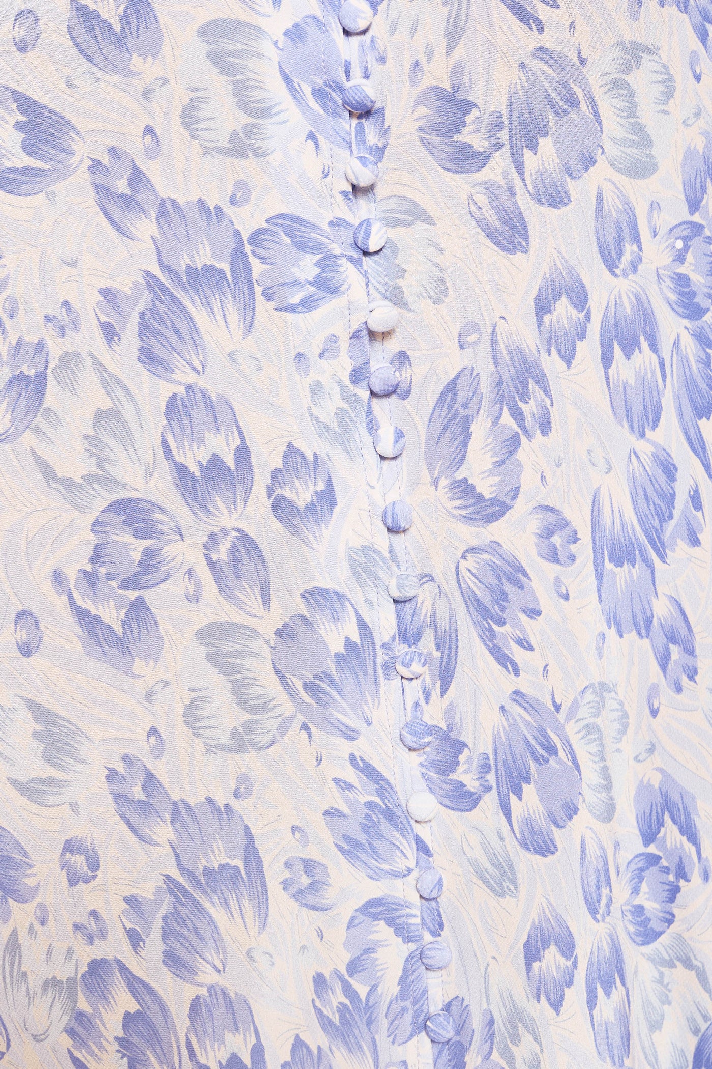 Close-up of the Katie dress in Tulip Fields Cornflower Blue—crafted from light fabric with a delicate lavender floral pattern and small, fabric-covered buttons. A perfect spring and summer style.