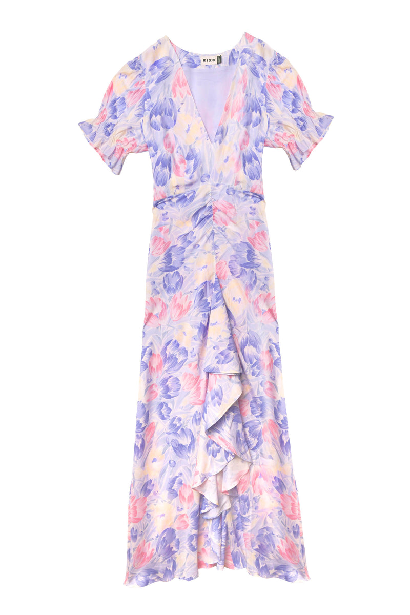 The Ariel - Tulip Fields Blue dress is an ankle-length, vintage-inspired design with short sleeves, a V-neck, pastel pink/purple/blue tulip print, ruffled front details, and a fitted waist—ideal for special occasions.