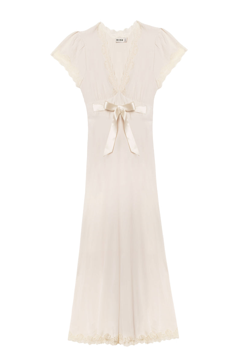 The Marlice - Pearl is an elegant, ivory vintage-inspired dress featuring short sleeves, lace trim on the neckline, sleeves and hem, a deep V-neck, and a satin bow waist for a timeless look.
