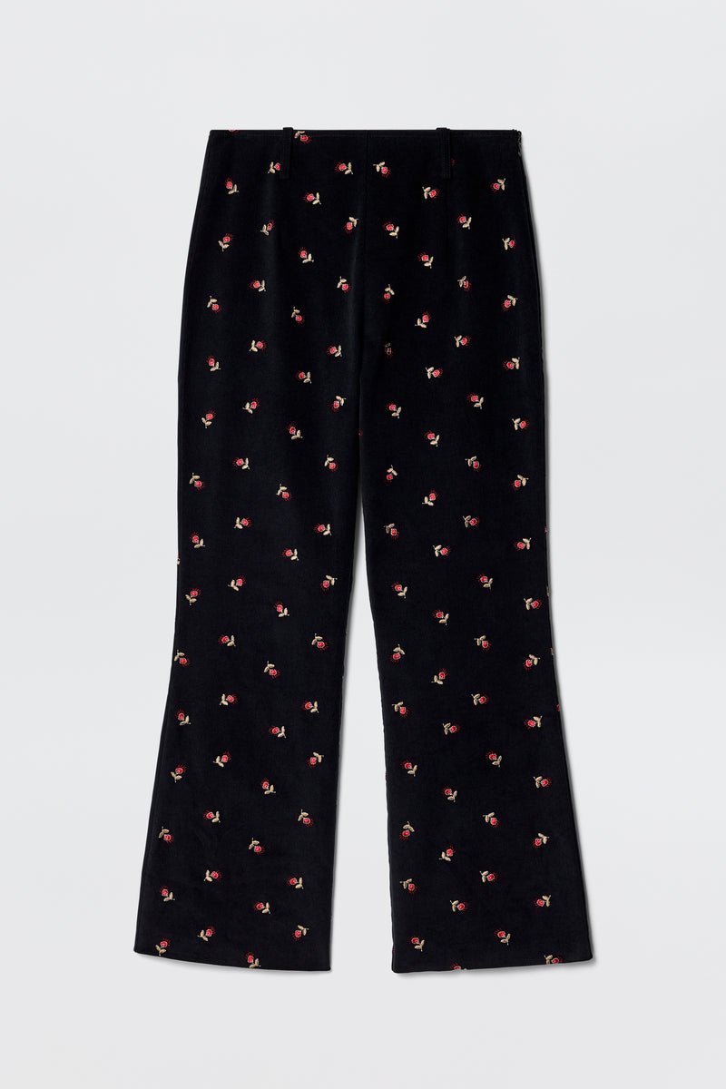 Olwen - Dandy Embroidery Deep Navy fit and flare trousers in black velvet, straight leg, with small red and green embroidered flowers. Vintage-inspired tailoring style shown laid flat on a light gray background.