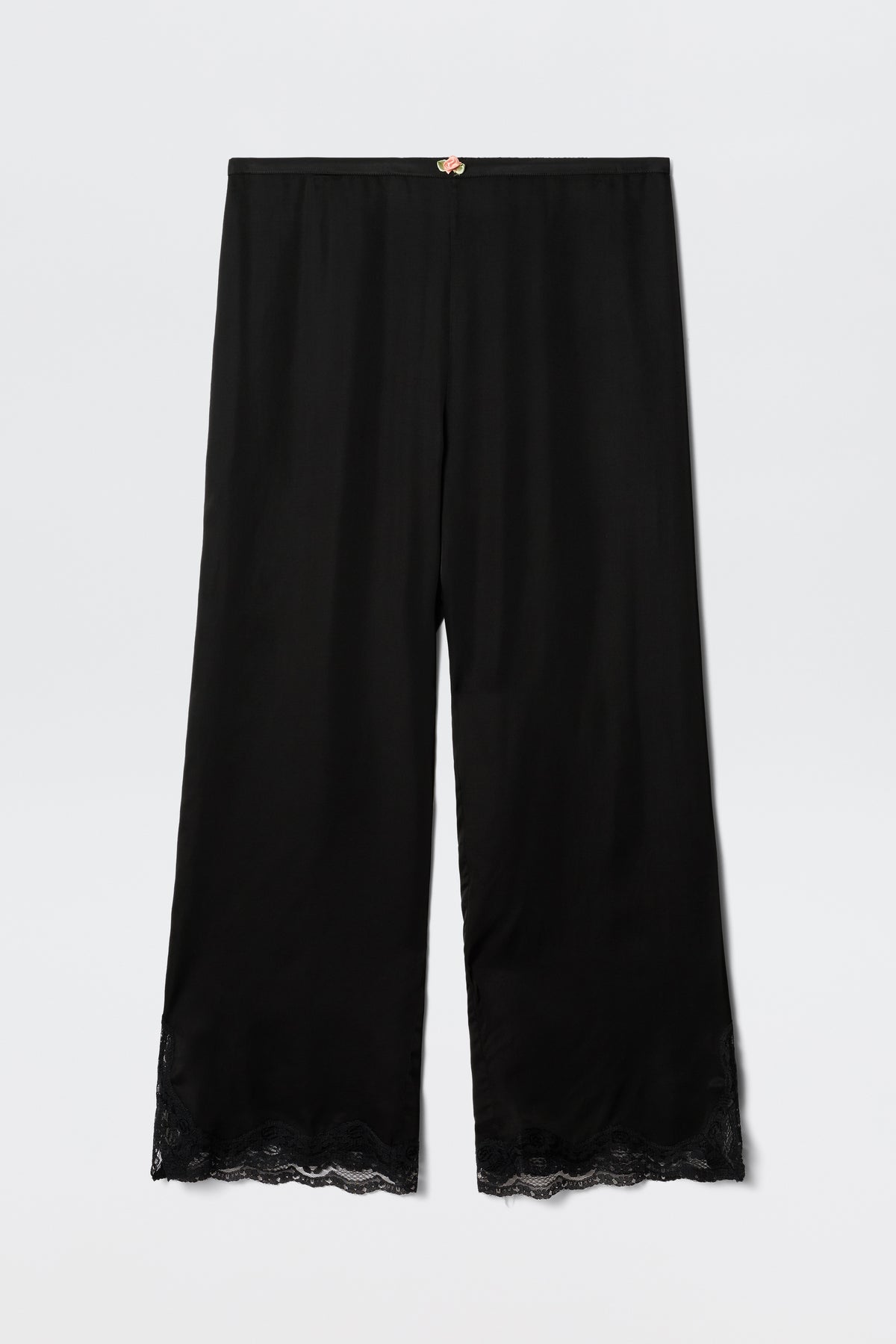 The Mireille - Black satin pajama pants feature a relaxed fit, lace-trimmed hem, and a small decorative bow at the waistband, shown against a plain white background.