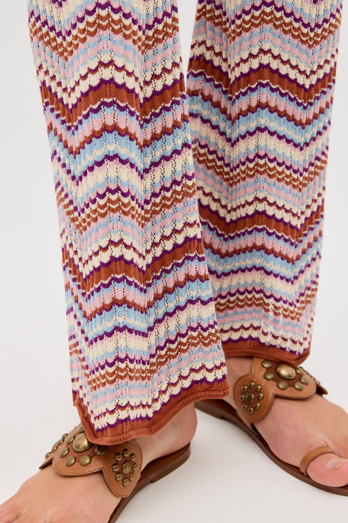 Close-up of a person wearing the Boni - Maria Chevron Multi trousers, featuring a colorful zigzag knit pattern in shades of white, pink, purple, and brown—perfect for adding a vibrant touch to your everyday wardrobe.