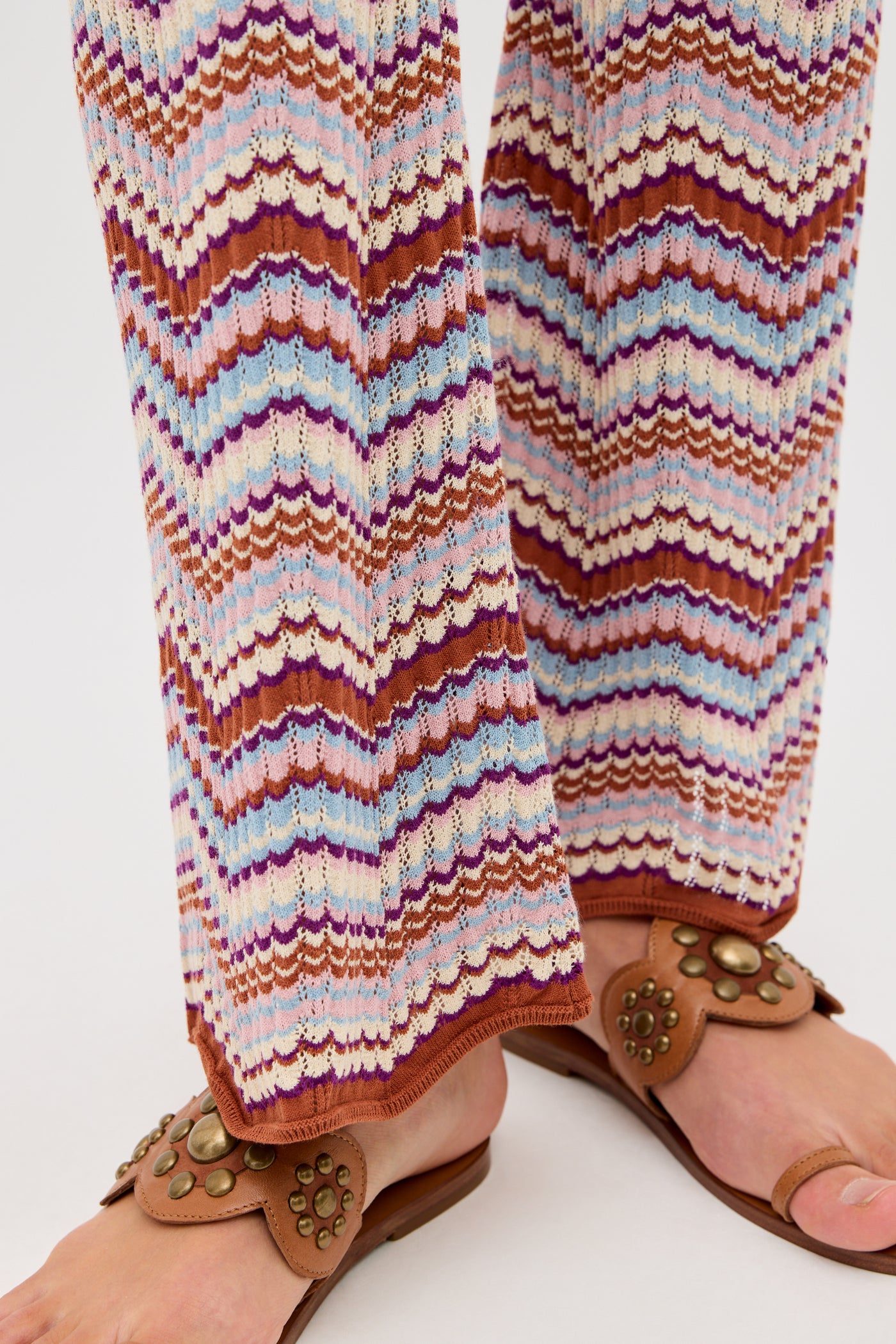 Close-up of a person wearing the Boni - Maria Chevron Multi trousers, featuring a colorful zigzag knit pattern in shades of white, pink, purple, and brown—perfect for adding a vibrant touch to your everyday wardrobe.
