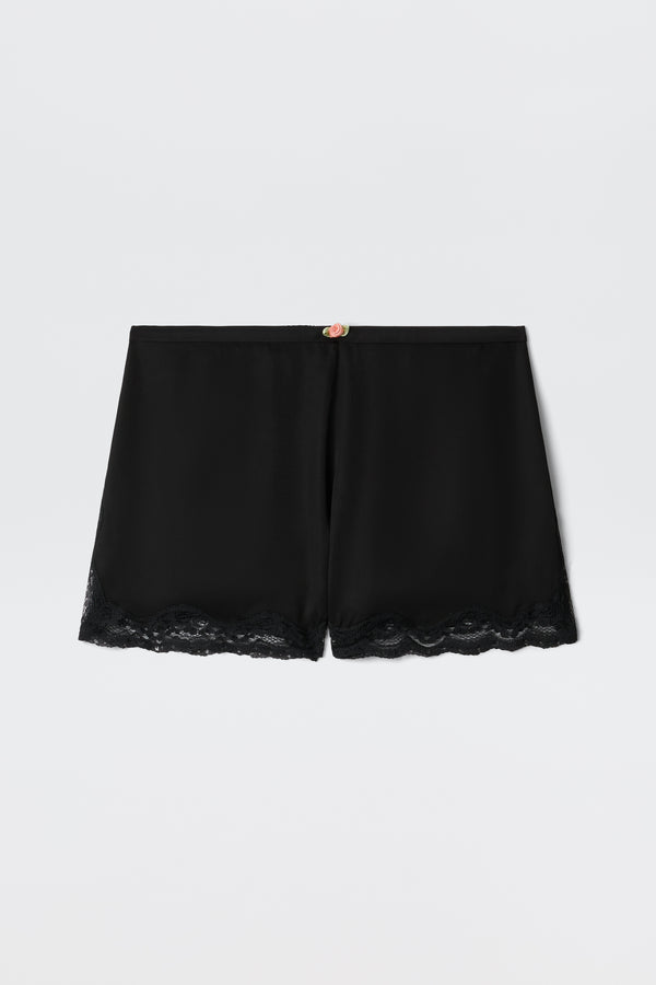 Lealia - Black satin shorts featuring a lace-trimmed hem and a delicate rose detail at the waistband, shown on a plain white background.