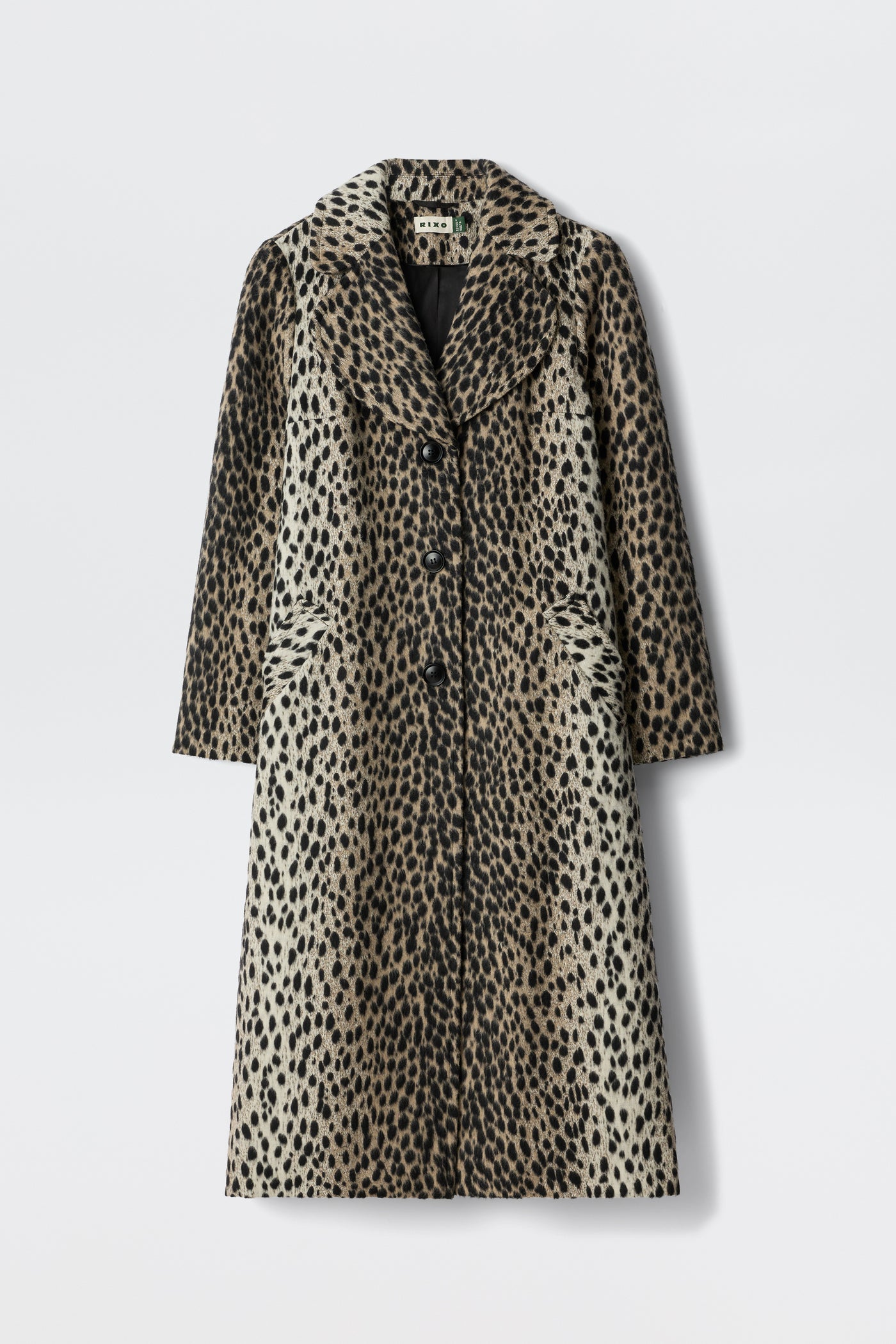 The Rosemary - Antelope Spot Jacquard Black is a long, knee-length coat with a spotted pattern, curved lapels, and three front buttons, shown against a plain white background.