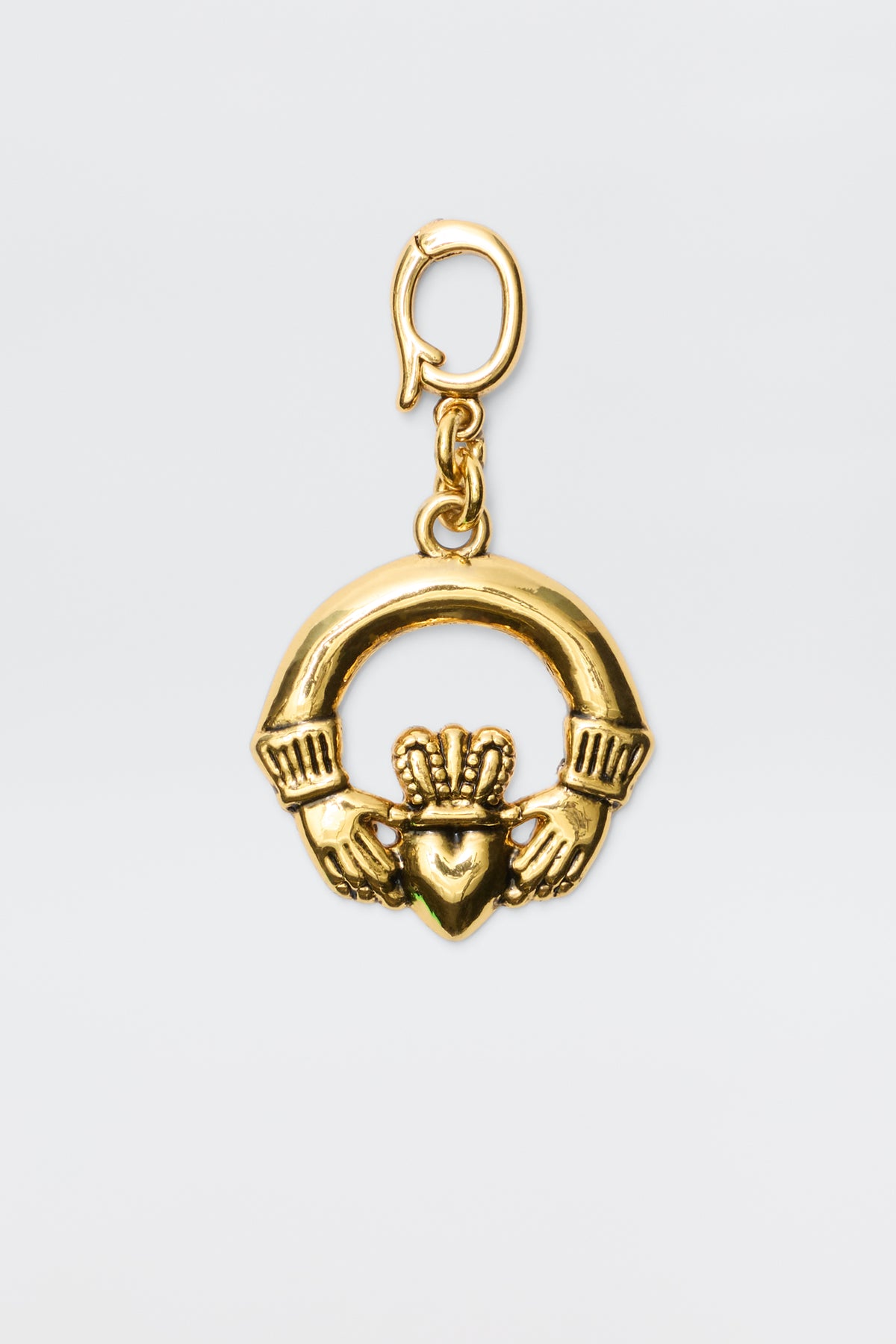 The Orsina - Gold is a gold-plated Irish Claddagh charm showing two hands holding a crowned heart, symbolizing love, loyalty, and friendship. It features a small clasp at the top for effortless chain attachment.