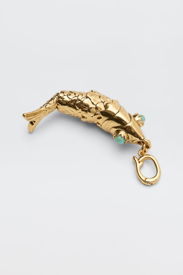Nerissa - Gold: A gold, fish-shaped pendant featuring detailed scales, turquoise eyes, and a clasp at the mouth, shown against a plain light background.