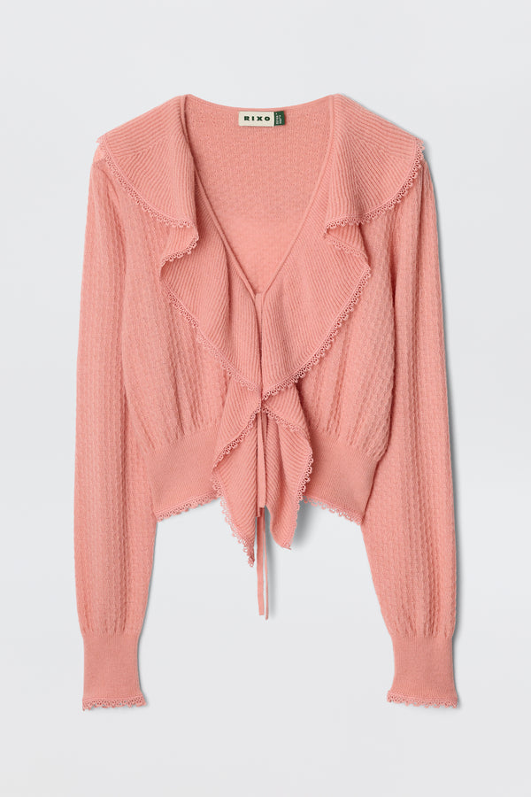 The Kianna - Blush is a pink transitional knit cardigan featuring a ruffled collar, long sleeves, front tie closure, textured pattern, and scalloped trim for a charming vintage look.