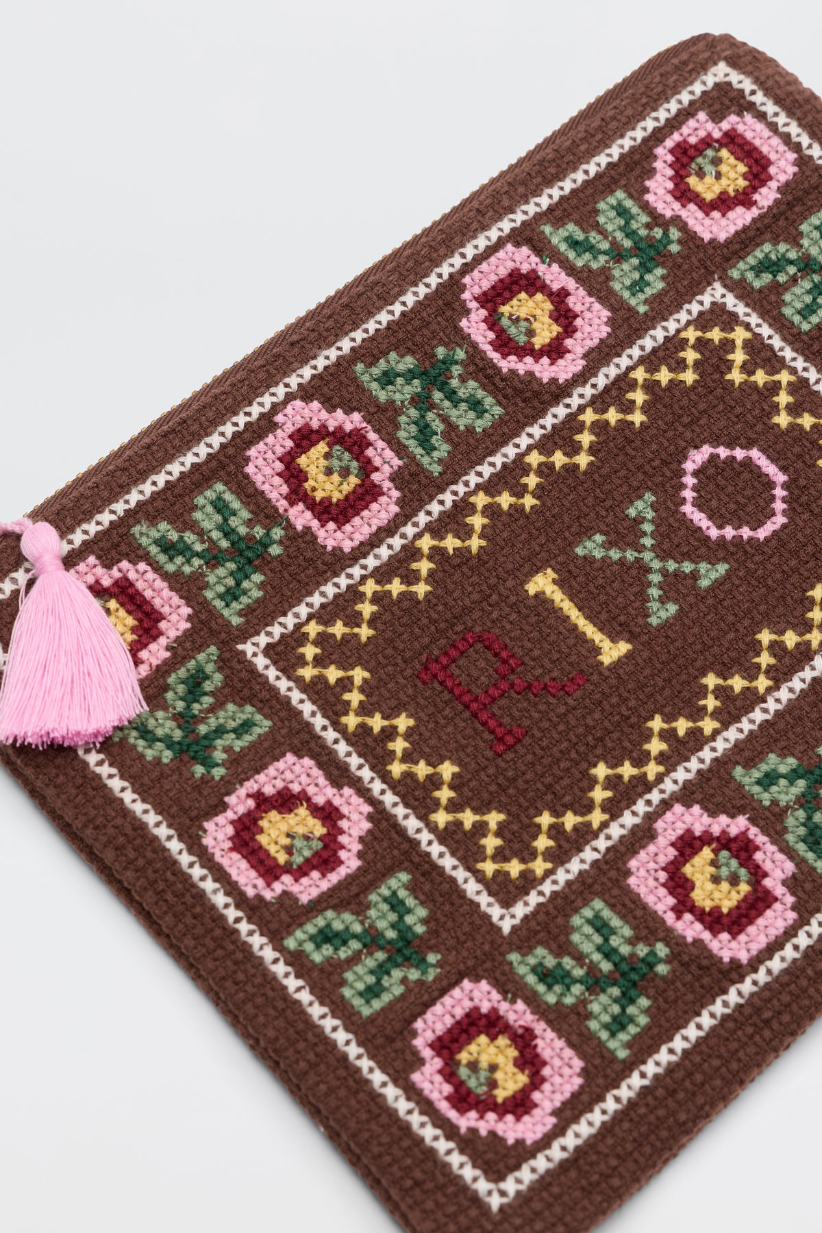 The Beau - Rosalia Cross Stitch Embroidery Brown is a brown woven pouch with pink and yellow floral designs, "PIX" stitched at the center, and a pink tassel on the zipper.