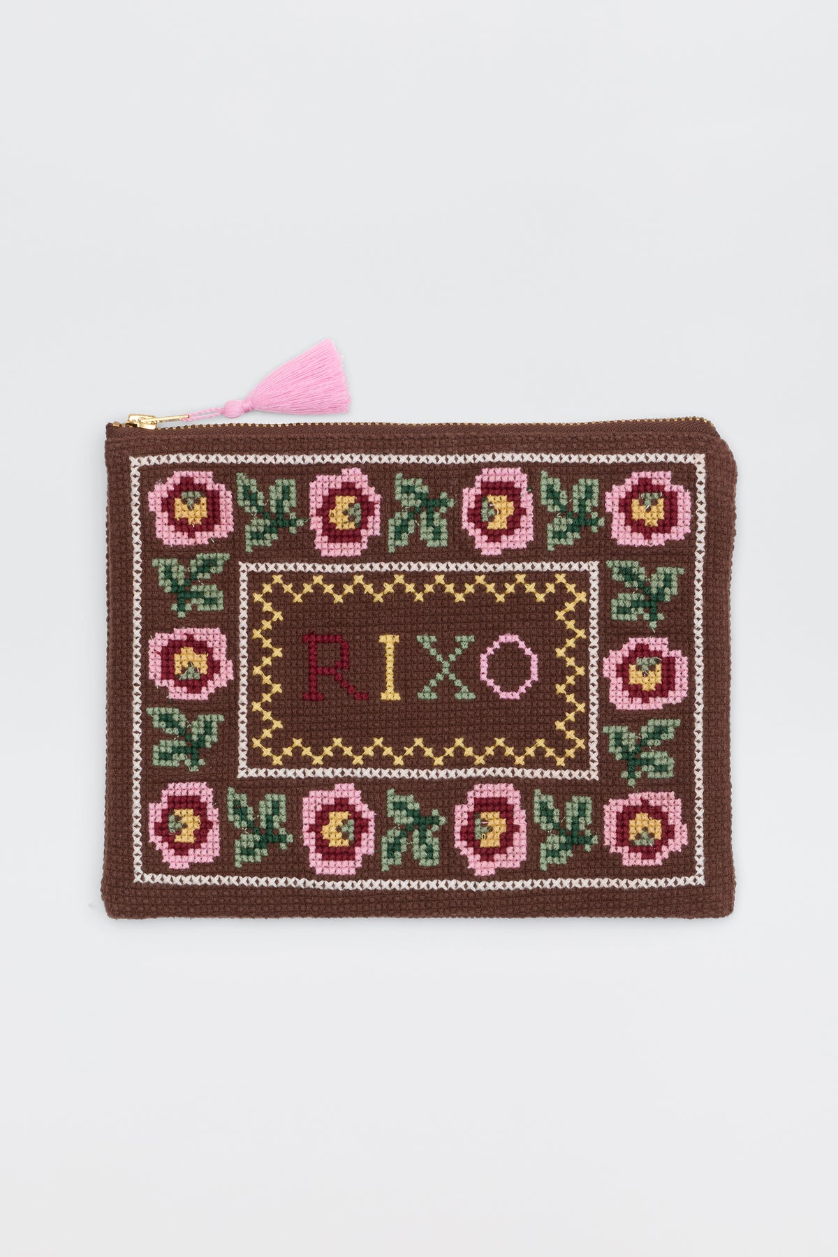 The Beau - Rosalia Cross Stitch Embroidery Brown is a rectangular brown zip pouch with a pink tassel, pink and green floral embroidery along the border, and "RIXO" stitched in the center.