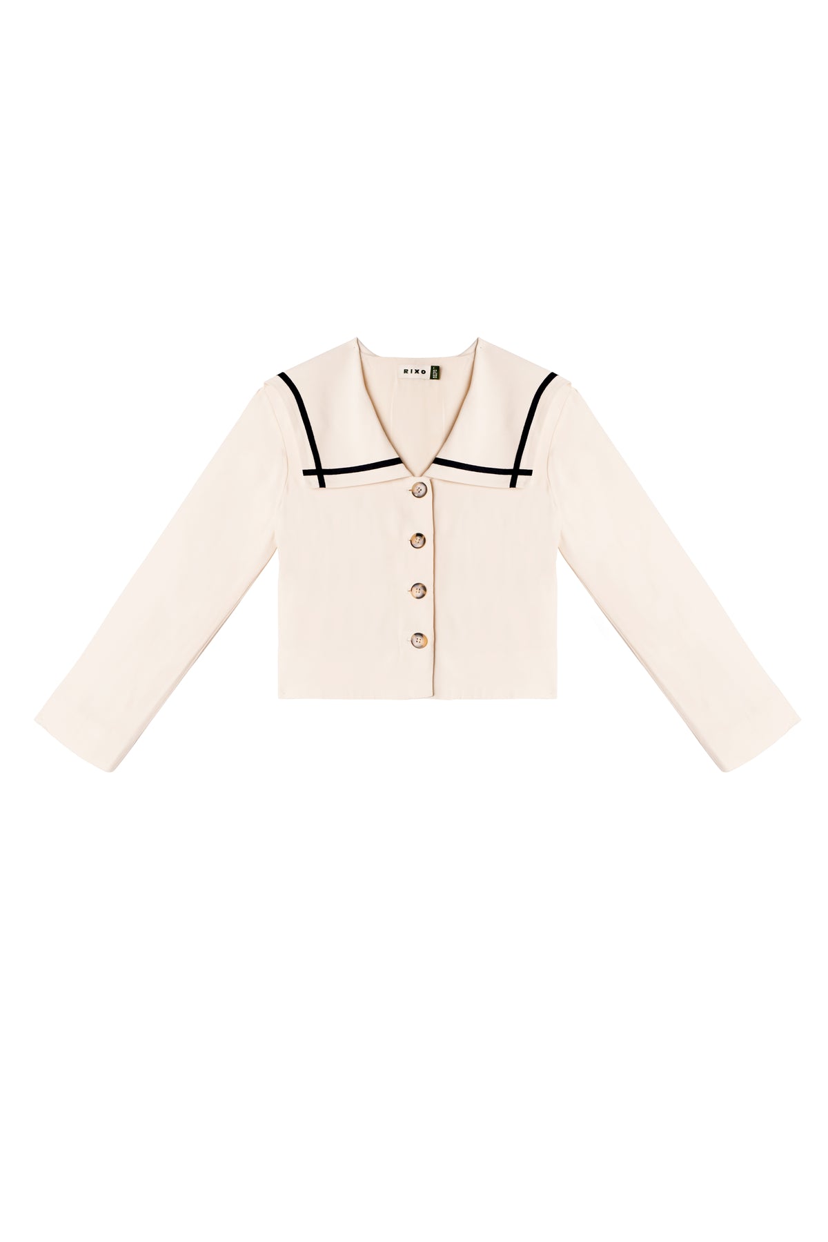 The Manon - Almond is a cream-colored, lightweight cropped jacket with long sleeves, wide collar, black trim accents, and four front buttons, offering a chic nautical-inspired look.