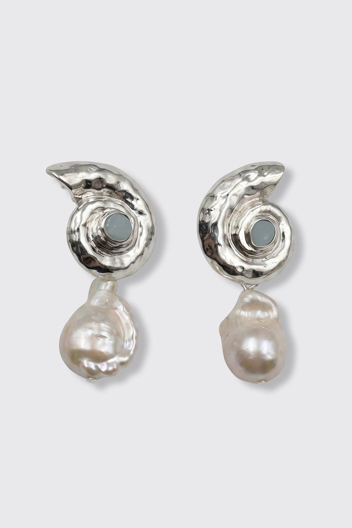 Two Cali - Silver earrings, featuring a spiral silver design with round gray stones at the center and large baroque pearls suspended below, displayed against a plain light gray background.
