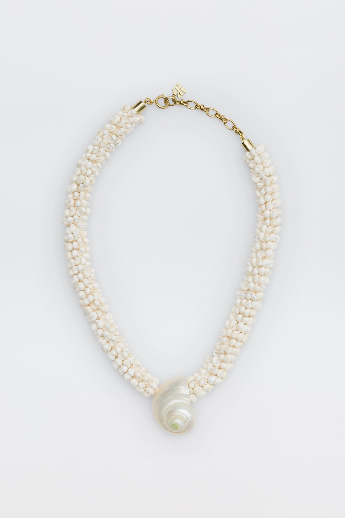 Imara - Pearl: A beaded necklace with small white beads, a large spiral seashell pendant, gold clasp, and adjustable chain, displayed on a white background.