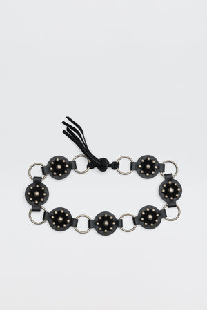 Introducing Kassy - Black: a black bracelet composed of circular segments adorned with small gold studs, linked by silver rings, and finished with a black string tie.
