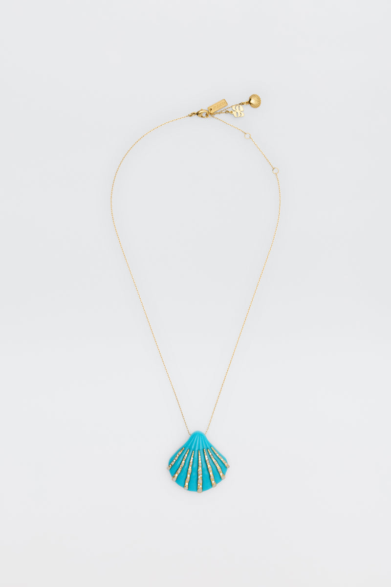 The Leanira - Turquoise necklace features a delicate gold chain with a blue seashell-shaped pendant accented in gold, shown on a plain white background.