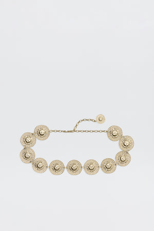 Leyla - Gold is a gold chain belt with round, ornate medallions linked together, each featuring intricate textured detailing and an adjustable chain clasp, shown on a plain white background.