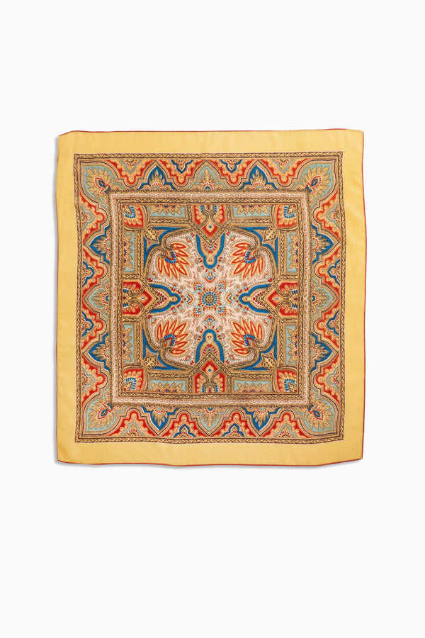 Menno - Paisley Golden is an elegant square silk scarf with a yellow border, showcasing intricate paisley patterns in red, blue, and orange tones. Its symmetrical and ornate central designs make it a timeless fashion accessory.
