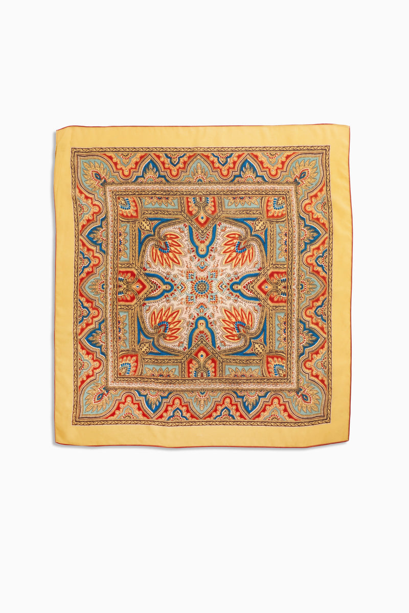 Menno - Paisley Golden is an elegant square silk scarf with a yellow border, showcasing intricate paisley patterns in red, blue, and orange tones. Its symmetrical and ornate central designs make it a timeless fashion accessory.