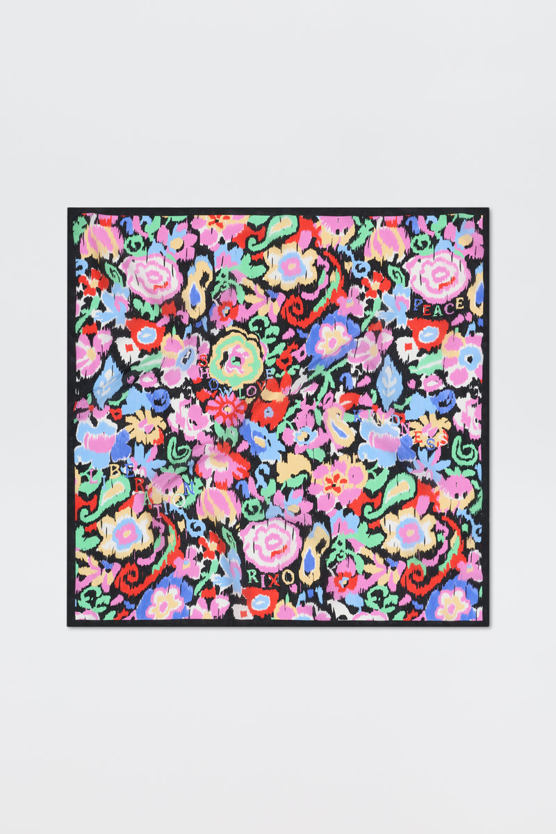 Introducing “Menno - Ikat Bloom”: a colorful square scarf featuring a vibrant floral pattern with words like LOVE, PEACE, and XOXO scattered among red, pink, blue, and green flowers on a black background.