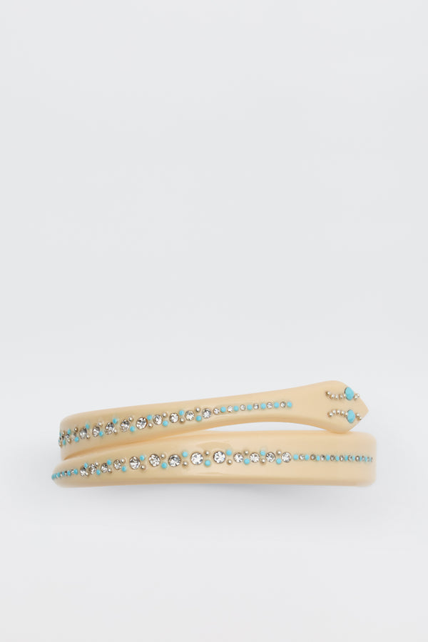 The Shereen - Cream headband features rows of small, round turquoise and clear rhinestones on a beige band, shown against a plain white background.
