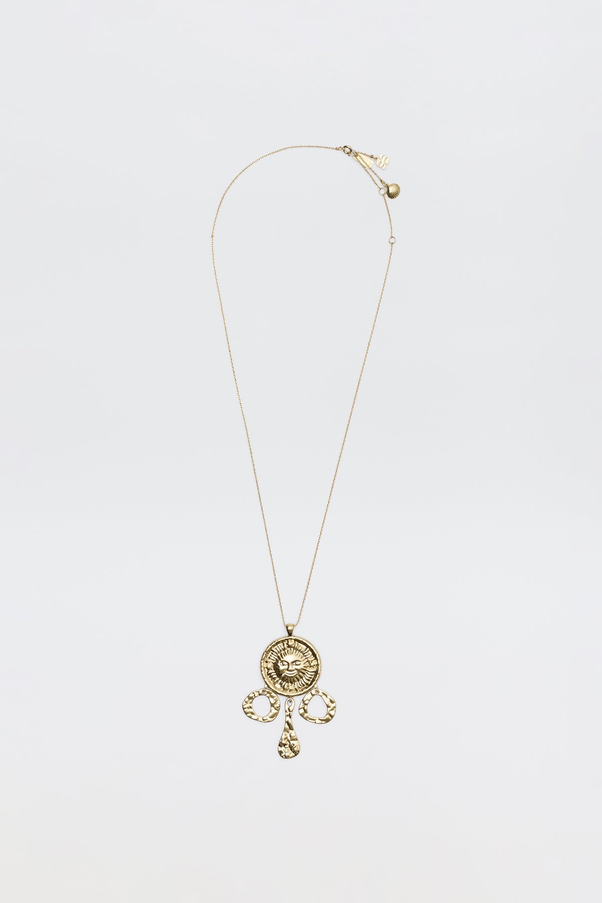 The Zahra - Gold necklace features a circular ornate pendant with intricate designs and three teardrop charms, shown against a plain white background.