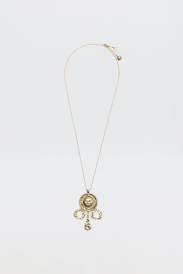 The Zahra - Gold necklace features a circular ornate pendant with intricate designs and three teardrop charms, shown against a plain white background.