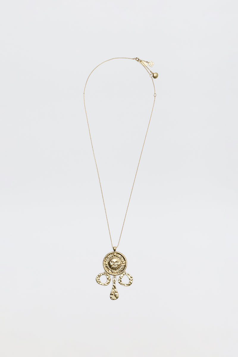 The Zahra - Gold necklace features a circular ornate pendant with intricate designs and three teardrop charms, shown against a plain white background.