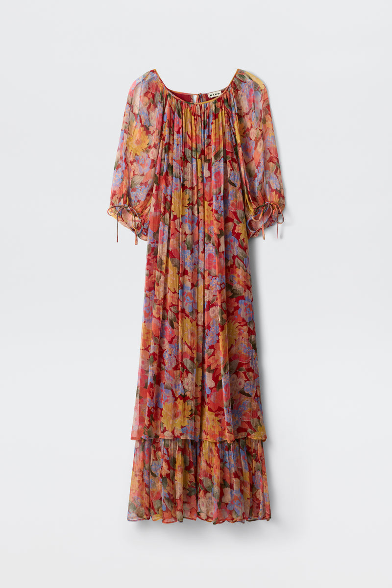 The Hayden - Chelsea Floral Red is a long, flowy dress adorned with a vibrant floral pattern in shades of red, orange, blue, and purple. It features puffed half sleeves and a ruffled hem and is displayed against a plain white background.