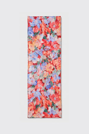 A rectangular scarf named “Julien - Chelsea Floral Red,” featuring a vibrant floral pattern in red, blue, pink, and green hues, is displayed flat on a light gray background.