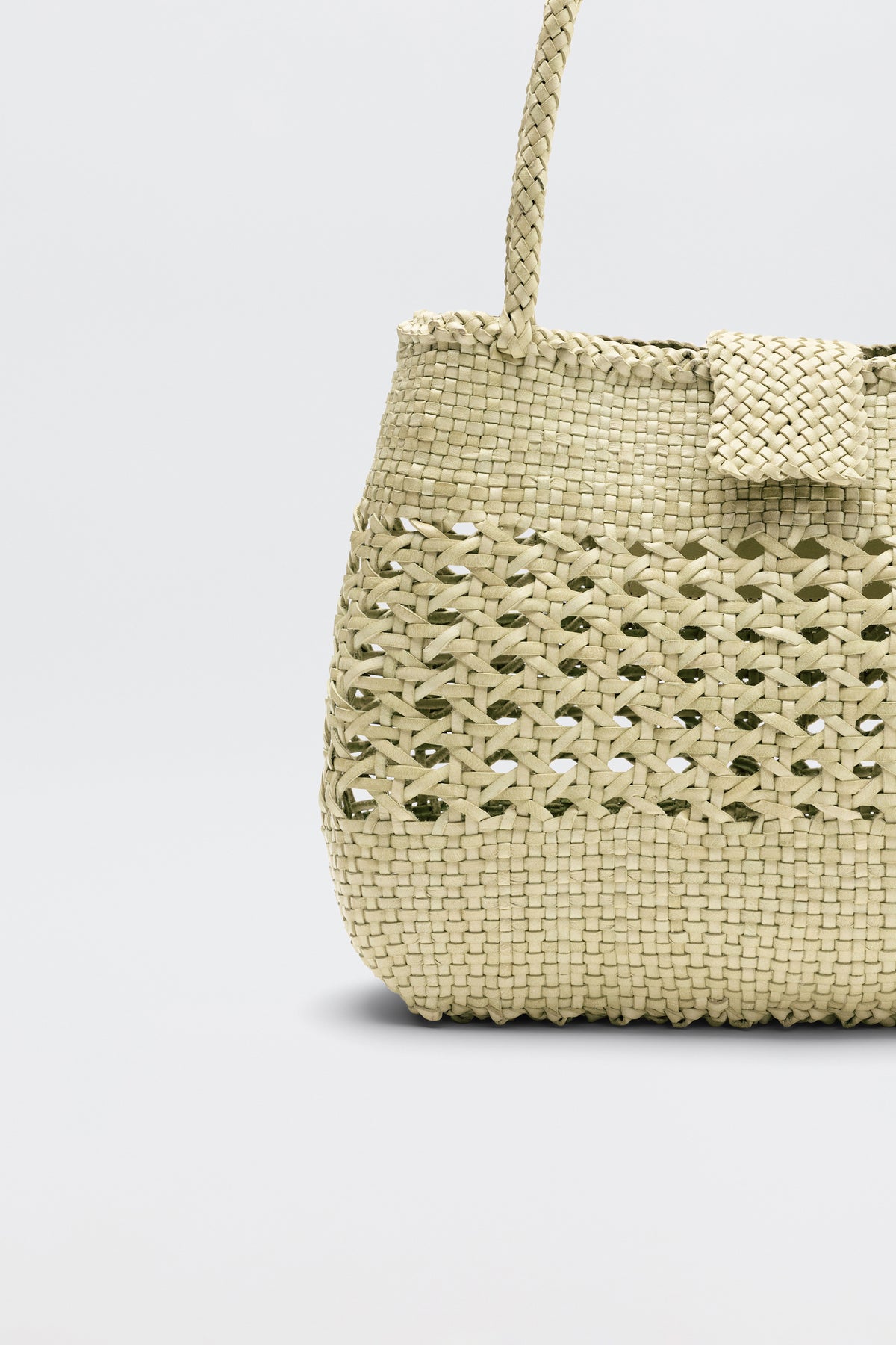A woven straw handbag named “Niamh - Butter” featuring a textured pattern and handle, reminiscent of vintage woven bags like the Dragon Diffusion Niamh bag, displayed against a plain light gray background.